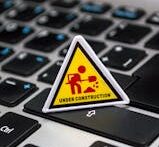 A miniature under construction sign placed on a laptop keyboard symbolizing digital development.
